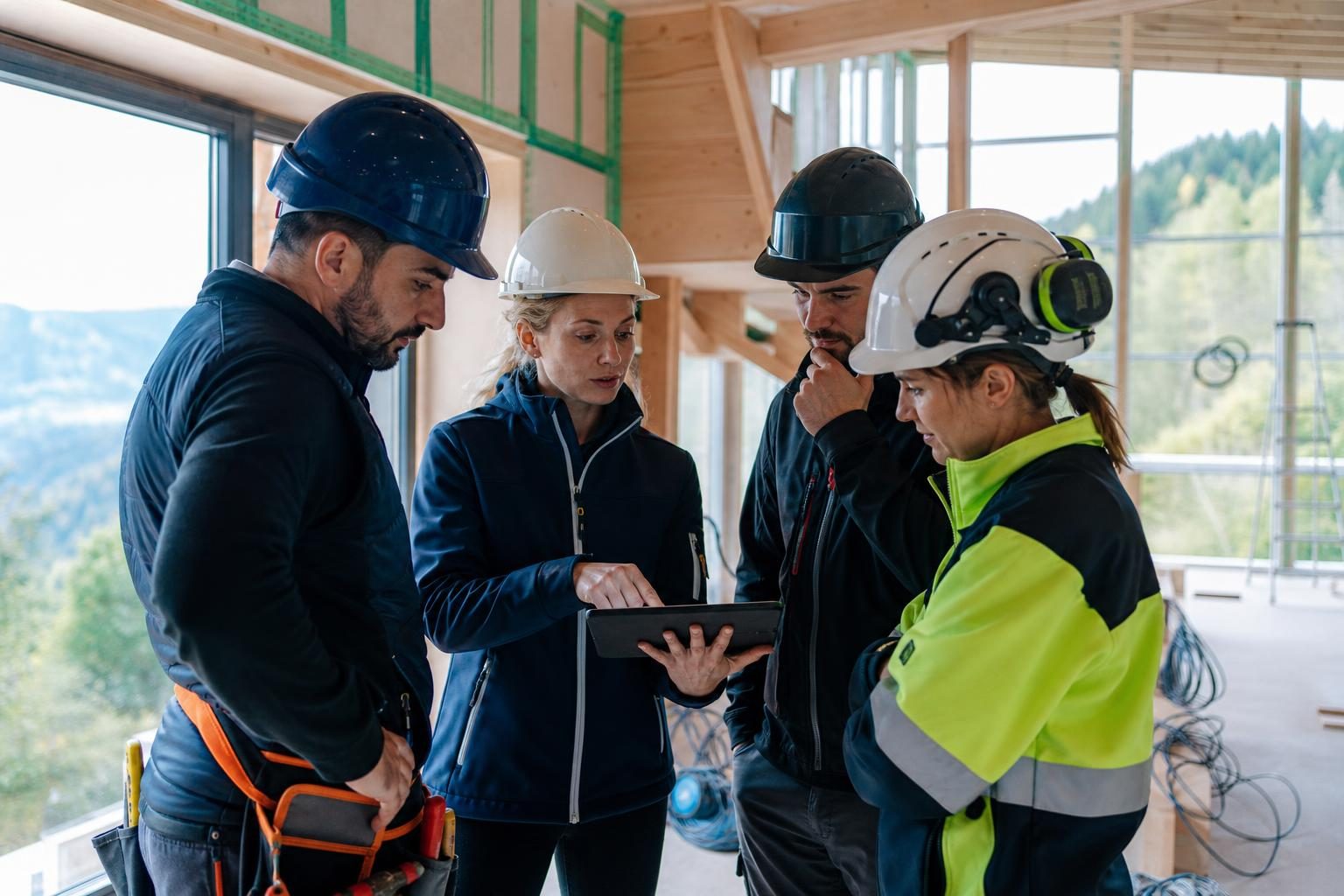 Construction workers and a site supervisor reviewing plans inside a partly completed European building.