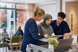 Care workers discussing their shift in a bright residential care facility in Germany.